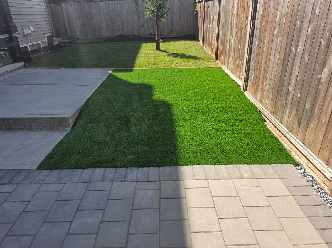 Finished paver patio beside artificial turf in a fenced Surrey backyard
